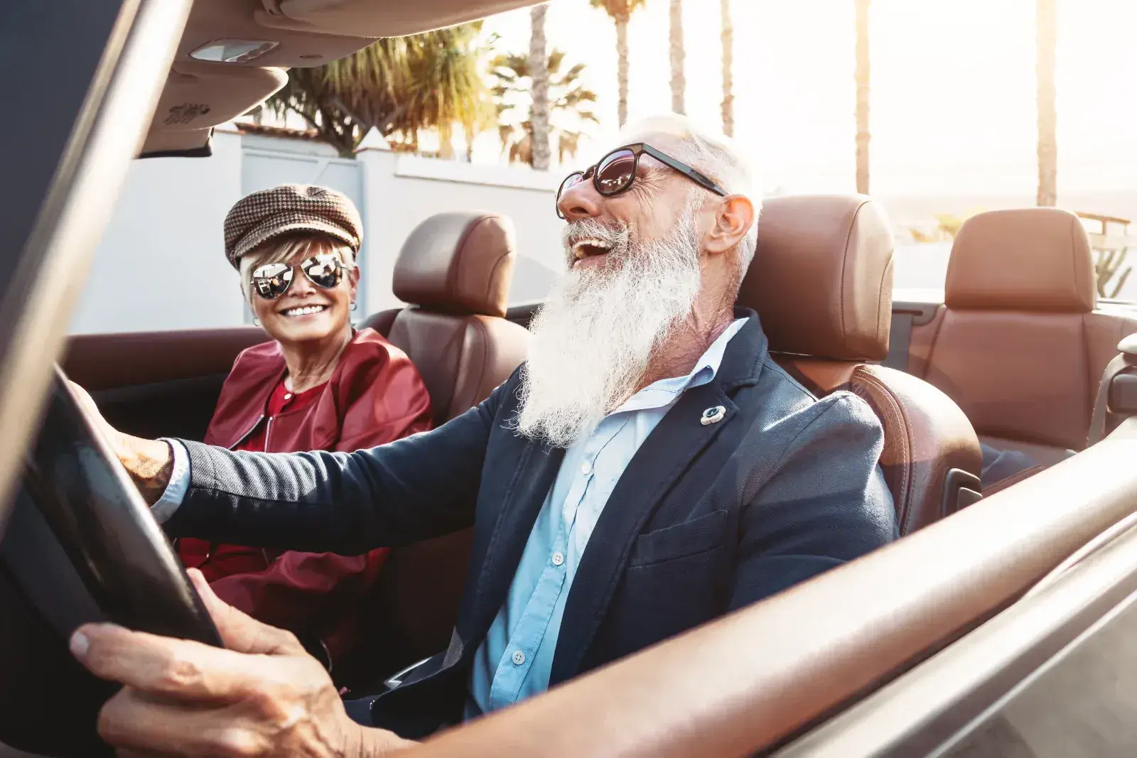 A retired couple laughing in a convertible