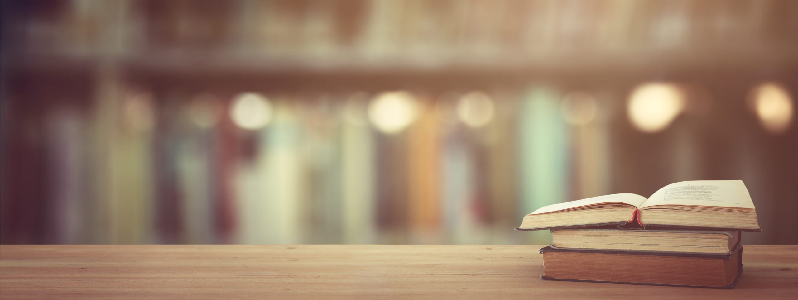 back to school concept. stack of books over wooden desk in front of ...